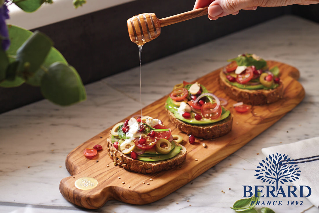 Berard wood board with avocado toast being drizzled with honey.