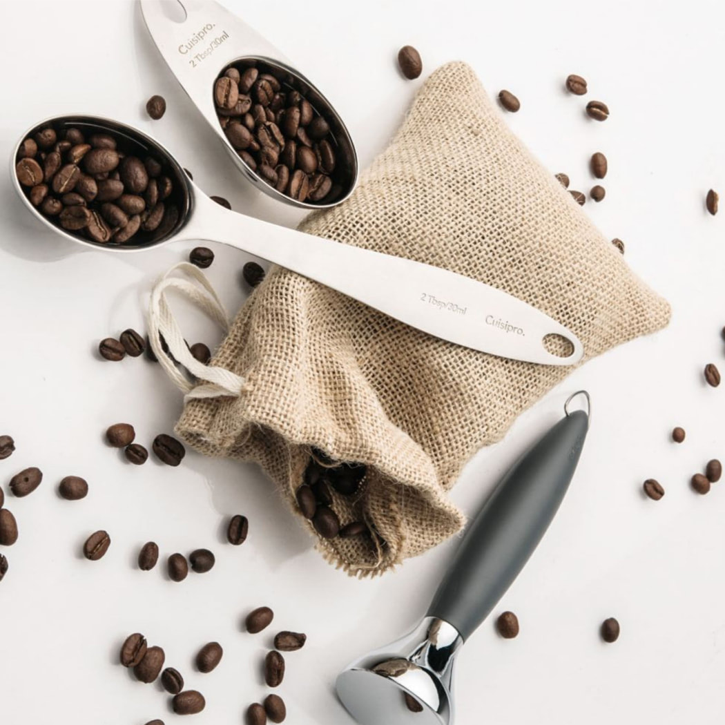 Cuisipro tamper and scoops on a table with coffee beans